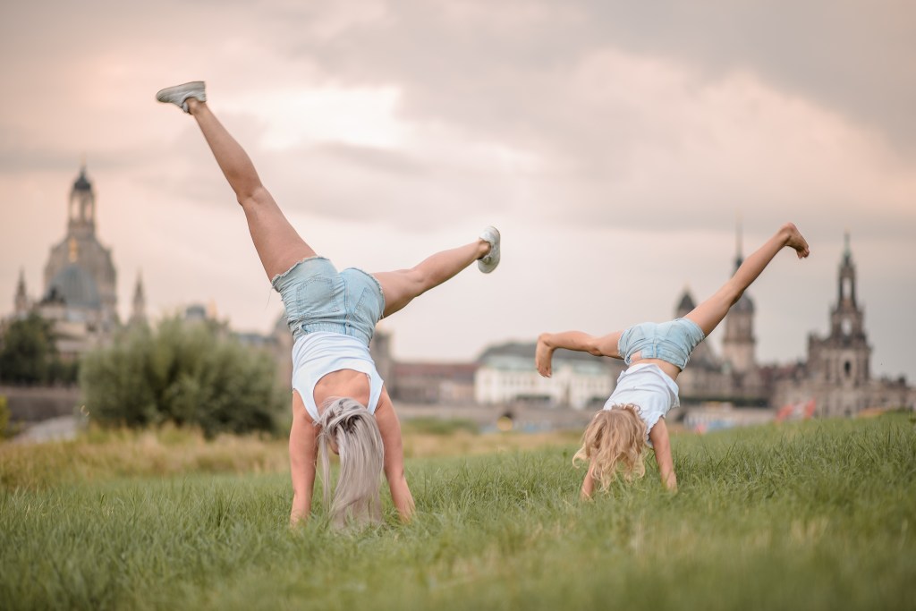 SIU - starke Perspektiven - Mutter und Kind machen synchron einen Handstand für der Kulisse der Dresdner Altstadt, die Szenerie ist in warmes Licht getaucht. 